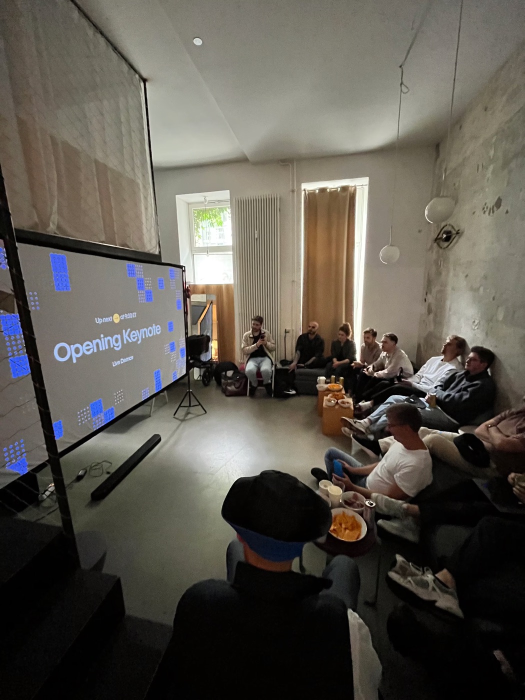 Die Opening Keynote läuft auf der Leinwand, die Gruppe schaut von Sofas und Sitzsäcken aus zu